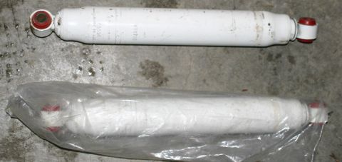 2003 Jeep TJ - Two white shock absorbers are shown, one unwrapped and one in plastic packaging.
