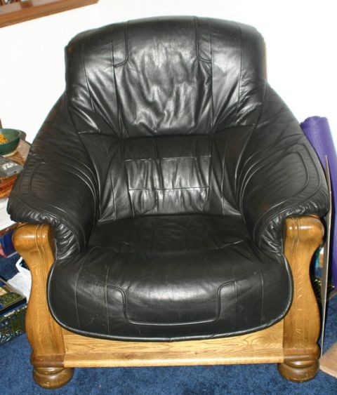 2003 Jeep TJ - A black leather armchair with carved wooden arms and base sits on a blue carpet.