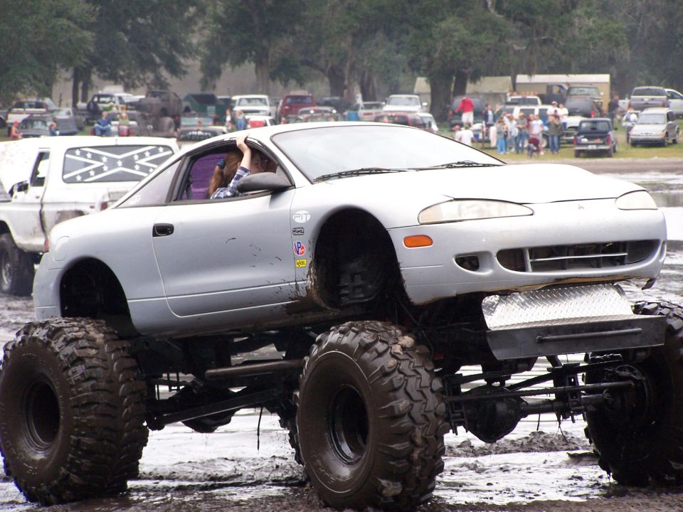 Silver car with large off-road tires and suspension lift, front 3/4 view