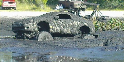 1987 Suzuki Samurai - A vehicle is submerged in thick mud, with only its basic shape discernible.