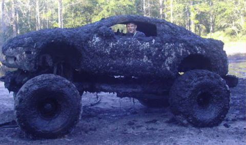 1987 Suzuki Samurai - This heavily mud-caked vehicle appears to be stuck in a muddy environment, with a person visible inside the cabin.