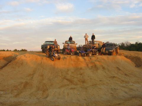 1986 Ford Bronco - A group of people and their off-road vehicles are gathered on a sandy hill under a cloudy sky.