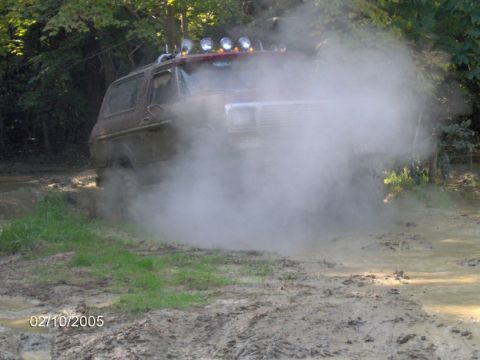 1978 Ford Bronco - This 1978 Ford Bronco is navigating a challenging muddy terrain, creating a cloud of dust.