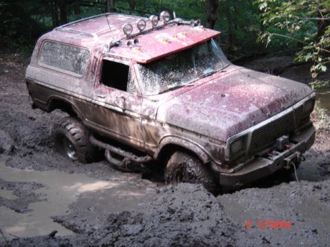1978 Ford Bronco - This maroon 1978 Ford Bronco is stuck deep in mud, with its front-right tire completely submerged.