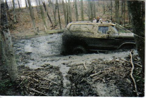 1978 Ford Bronco - This 1978 Ford Bronco is deep in a muddy forest trail, with water and debris splashing around it.