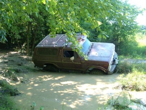 1978 Ford Bronco - This 1978 Ford Bronco is deep in the mud, surrounded by trees and vegetation.