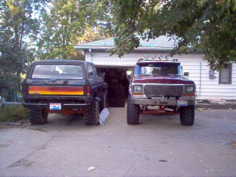 1978 Ford Bronco - Two modified Ford trucks, a Bronco and a pickup, are parked in a driveway in front of a residential garage.