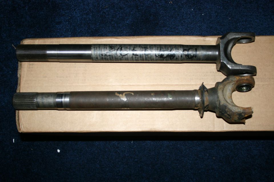 Two metal axle shafts, one with a U-joint, resting on cardboard