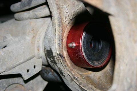 2003 Jeep TJ - This is a close-up view of a red bushing installed in a vehicle's axle housing, with a visible part number.