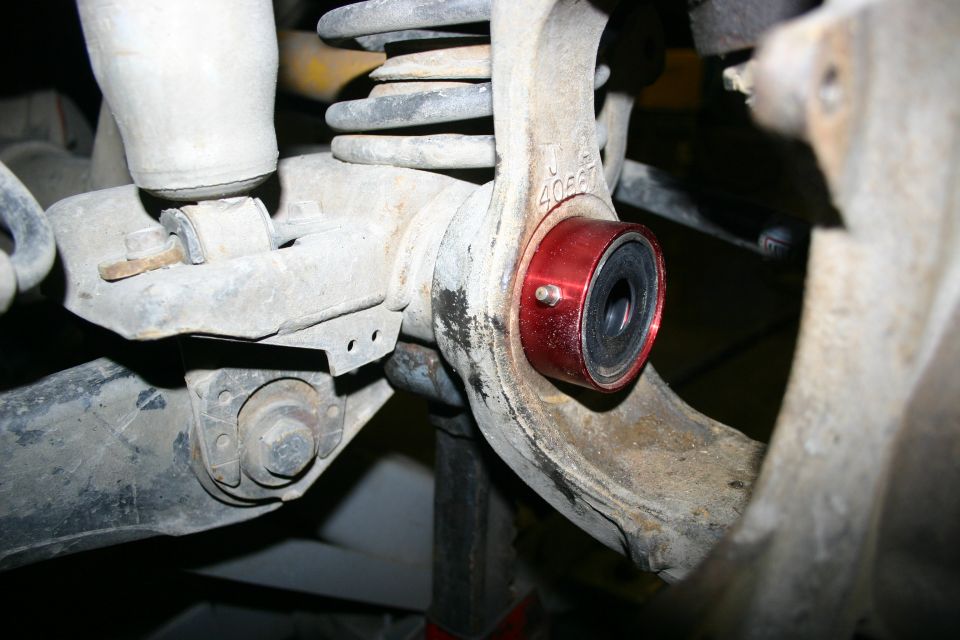 Close-up of a red aftermarket suspension bushing installed on a Jeep TJ axle