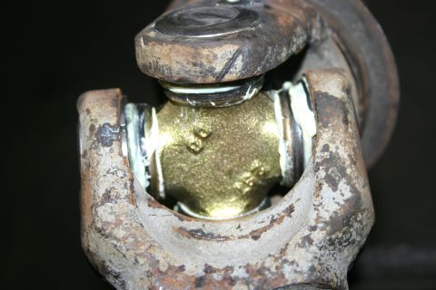 2003 Jeep TJ - A close-up view of a universal joint, showing the greased cross and bearing caps between two metal yokes.