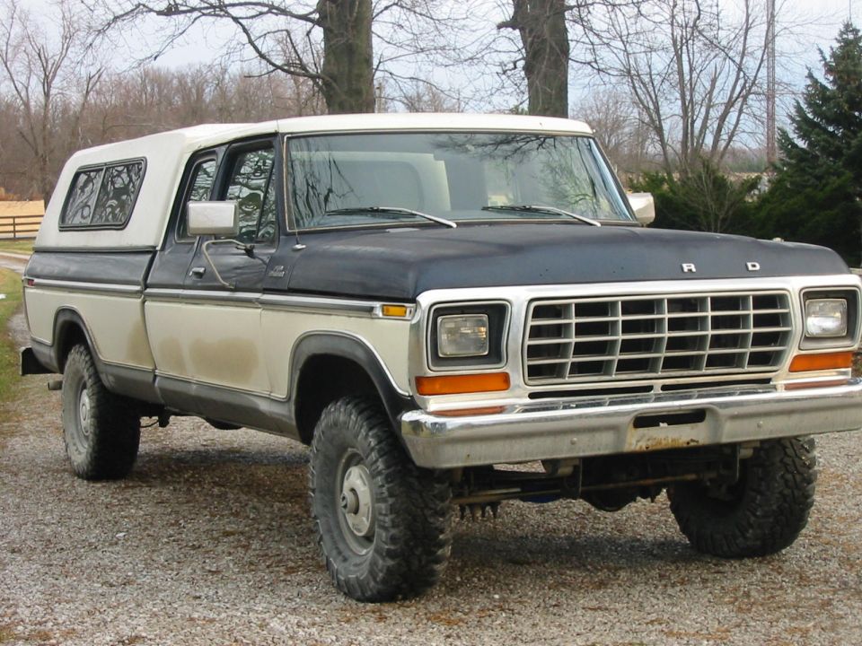 1978 Ford F-150 pickup truck with a white camper shell, parked on gravel