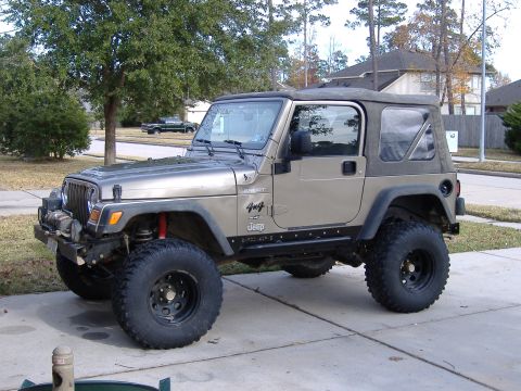 2004 Jeep Wrangler - This Jeep Wrangler is parked on a paved driveway with a suburban house and trees in the background.