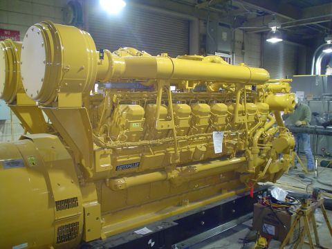 1966 International School Bus - A large yellow Caterpillar engine is shown in a workshop setting, with a person working in the background.