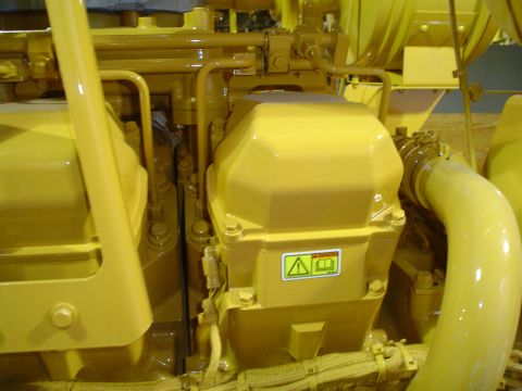 1966 International School Bus - A close-up view of yellow engine components, a warning sticker and the Supermotors.net logo.