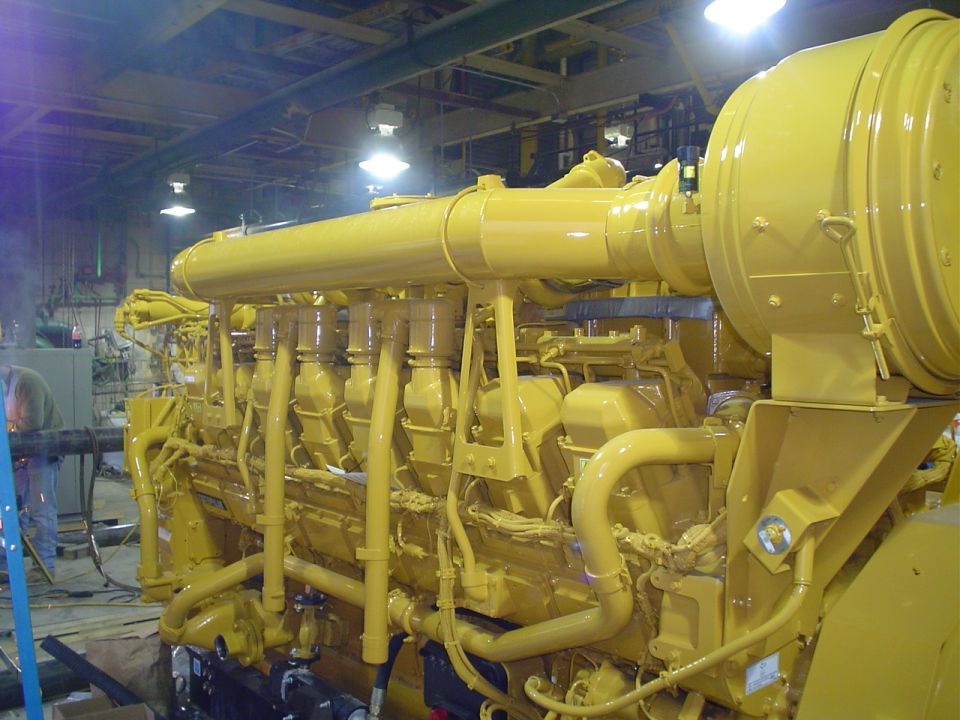 Large yellow engine with multiple exhaust pipes and a large cylindrical air intake
