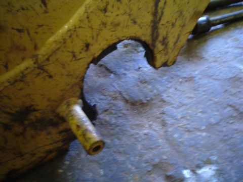 1966 International School Bus - A close-up view of a yellow metal component with a hollow cylindrical extension, set against a rough, blue-grey surface.
