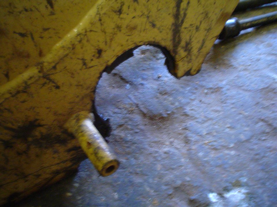Yellow metal part with a cylindrical protrusion and a hole, resting on a textured surface