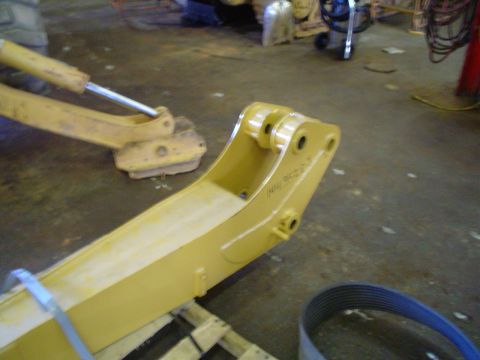 1966 International School Bus - Close-up of a yellow excavator boom arm, showing part numbers stamped into the metal.