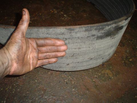 1966 International School Bus - A mechanic's dirty hand is shown next to a large, worn V-belt, likely for a heavy-duty vehicle.