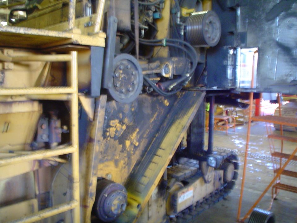 Yellow construction equipment with tracks and hydraulic hoses