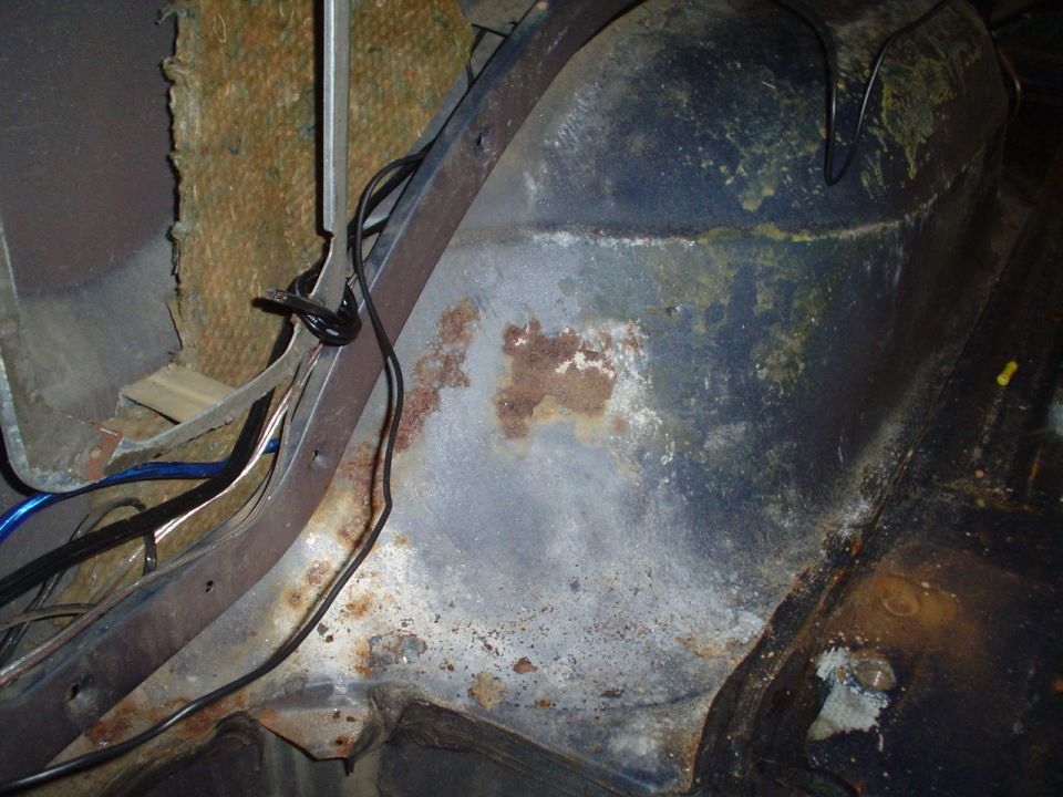 Rusted interior panel with exposed wiring and insulation