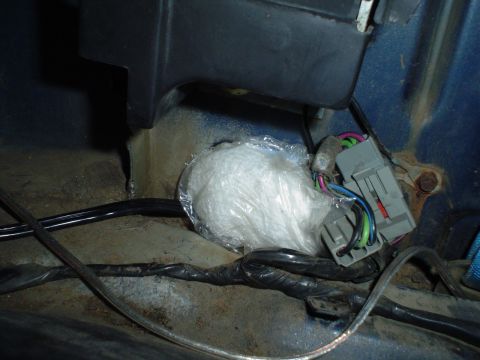 1984 Ford Bronco - Close-up of a wrapped object and wiring harness connector inside a vehicle.