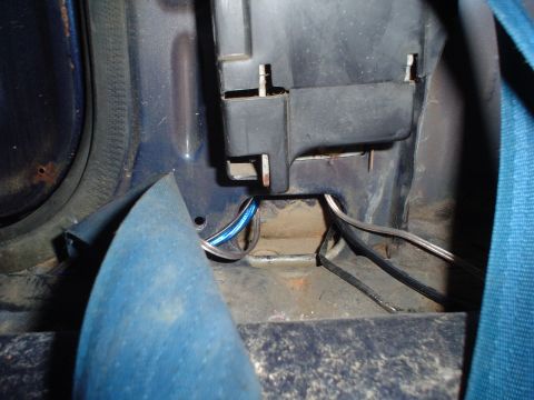 1984 Ford Bronco - Wiring is visible beneath a black plastic component and near a blue seatbelt in the vehicle's interior.