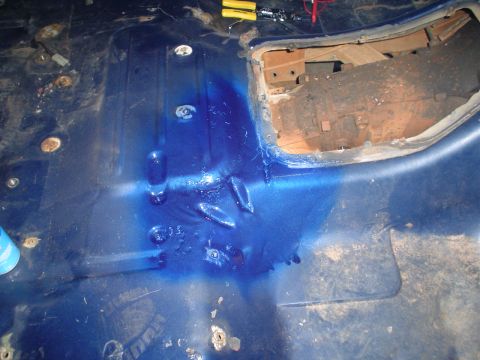 1984 Ford Bronco - The interior floor of a vehicle shows signs of rust and a section removed to access internal mechanics.