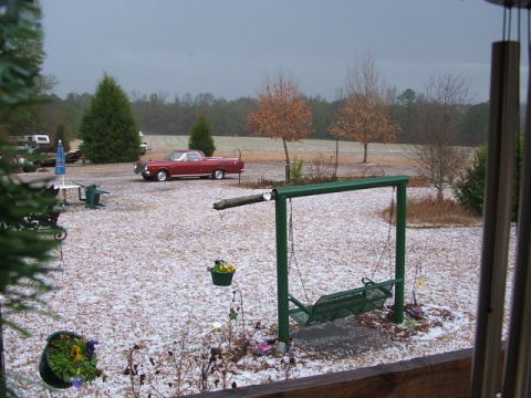 1966 Ford Ranchero - A dark red car-based pickup with a white roof sits in a gravel yard blanketed in hail or light snow, photographed from a covered porch past…