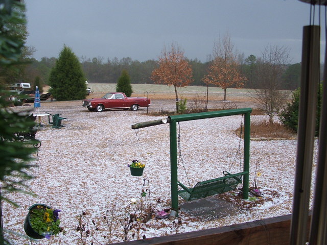 Dark red car-based pickup parked in a hail-covered yard seen from a porch