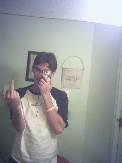 1994 Ford Probe - Man takes a mirror selfie in a bathroom, holding a camera and giving the middle finger.