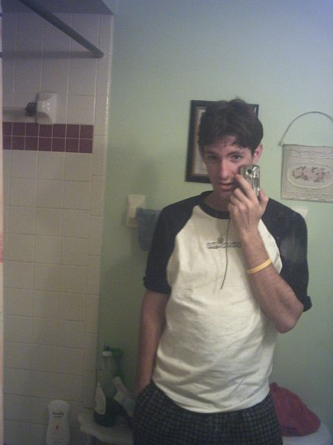1994 Ford Probe - A man takes a mirror selfie in a bathroom, holding a flip phone to take the picture.