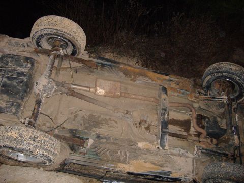 1996 Jeep Cherokee - The underside of a vehicle is visible after it has overturned, revealing its suspension and exhaust components.