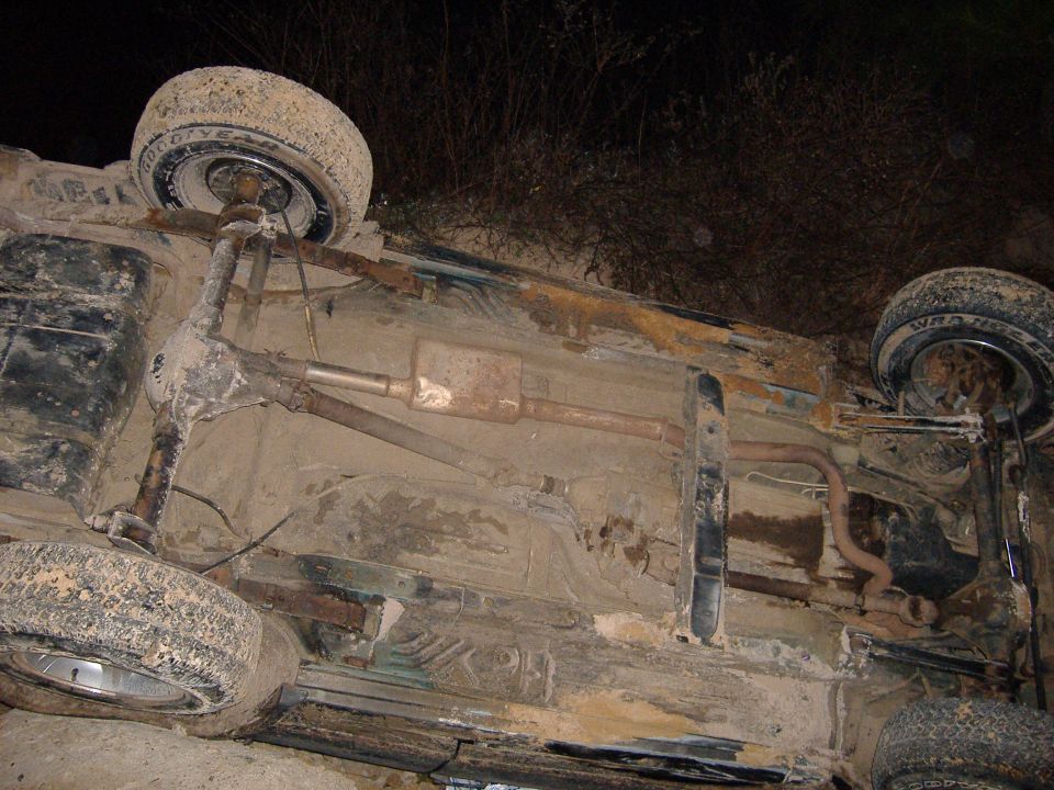 Underside of overturned vehicle showing suspension and exhaust system