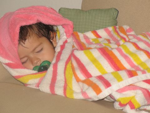 1984 Ford Bronco - A baby sleeps soundly, swaddled in a colorful striped blanket with a pacifier in its mouth.