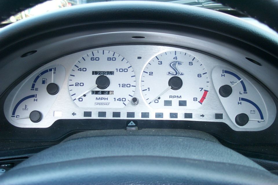 Aftermarket white-face Speedhut gauge cluster with Cobra logo tachometer and speedometer.