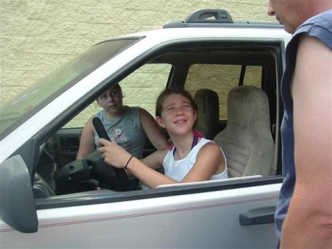 1991 Ford Bronco - Two girls are inside a white SUV, one at the wheel, with a man standing outside the passenger door.