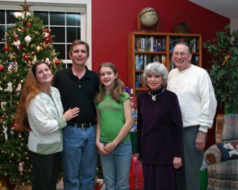 1991 Ford Bronco - A family gathers for a holiday photo in front of a decorated Christmas tree, with a bookshelf filled with books behind them.