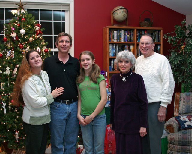 family in front of Christmas tree, bookshelf in background