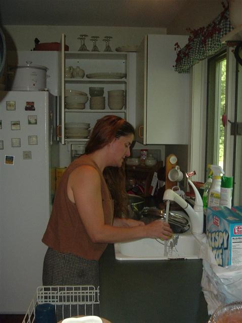 1991 Ford Bronco - A woman is doing dishes in a kitchen sink, with a refrigerator and cabinets visible.