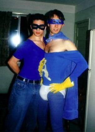 1991 Ford Bronco - Two men pose in matching blue superhero costumes, one wearing a cape and yellow gloves.