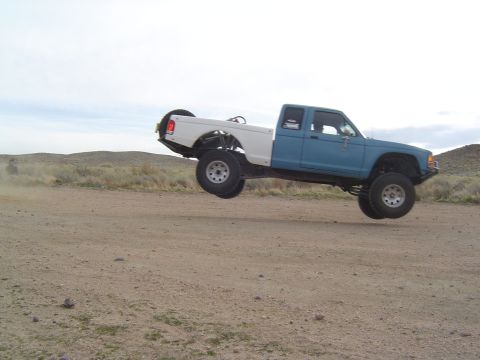1985 Ford Ranger - This modified pickup truck is captured mid-jump on a dusty, off-road terrain.