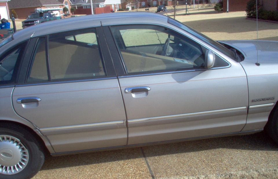 Silver four-door sedan side profile parked on pavement, full hubcaps and tinted windows