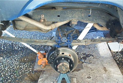 1986 Ford Bronco - Close-up view of the rear suspension and braking system of a vehicle undergoing maintenance.