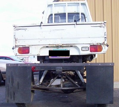 1995 Ford Bronco - Rear view of a white pickup truck a custom flatbed modification and exposed suspension.
