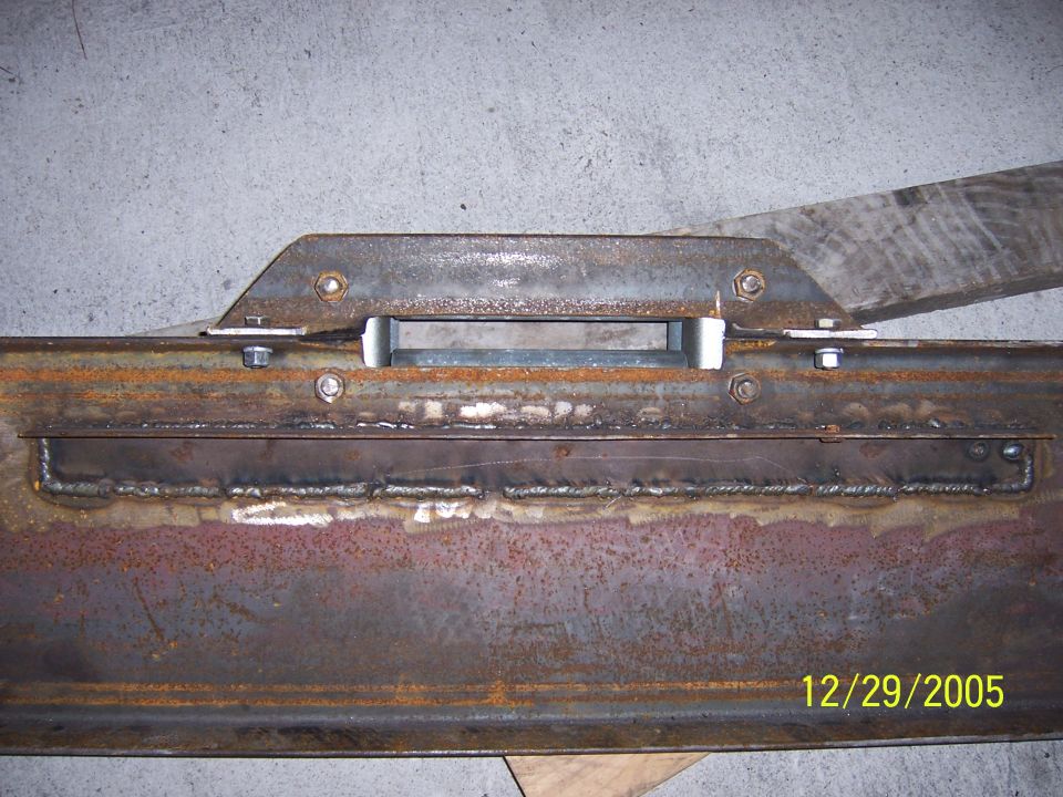 Welded steel frame crossmember with bracket and bolts on a concrete floor
