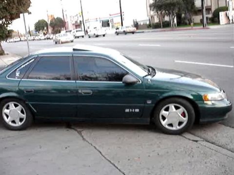 1993 Ford Taurus - Side view of a green 1993 Ford Taurus sedan parked on a street.