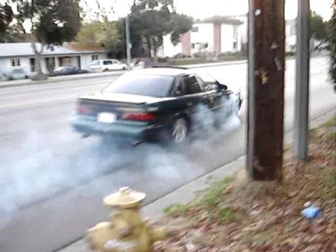 1993 Ford Taurus - A dark green 1993 Ford Taurus performs a burnout, kicking up smoke as it turns.