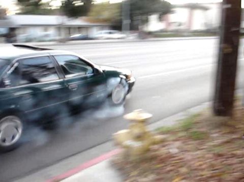 1993 Ford Taurus - A 1993 Ford Taurus performs a burnout, kicking up smoke from its tires on a suburban street.